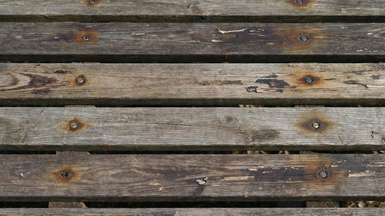 Weathered garden bench slats with recessed fixings and open drainage gaps